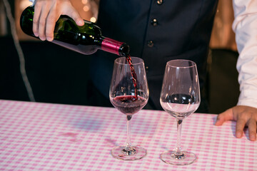 Waitress man pouring wine into glass