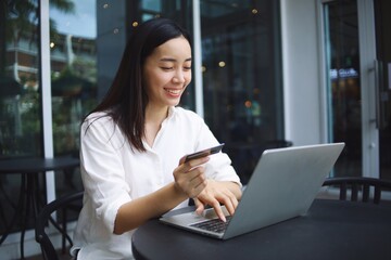 Happy Asian woman using laptop at outdoor.