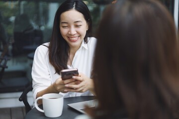 Woman smiling using smart phone in coffee shop.