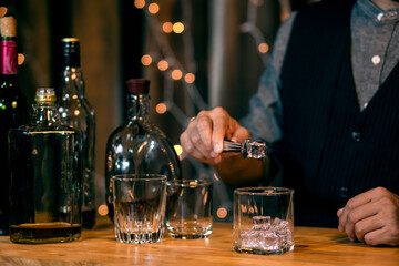 Waitress man standing pours whiskey into a glass 