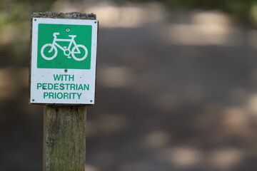 A green and white sign saying Cycling allowed with pedestrian priority
