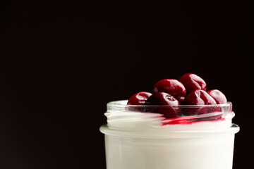 Dessert with fresh cherry close up on black background. Panna cotta with berries macro.