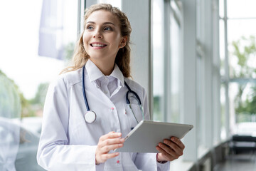 healthcare, technology and medicine concept - smiling female doctor with stethoscope taking notes...