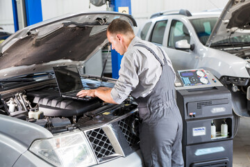 car service worker carries out diagnostics and car repairs in the room.