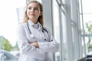 Portrait of young woman doctor with white coat standing in hospital.