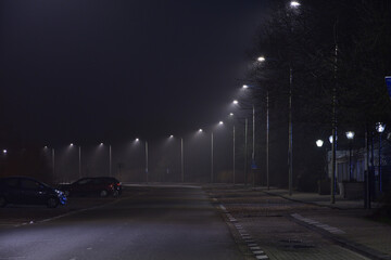 Street and glowing lamps on a foggy autumn evening.