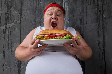 fat funny man opened his mouth to bite off a tidbit of a sandwich. hungry male leads unhealthy lifestyle, nutrition concept