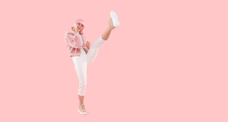 Fototapeta Girl power! Full length banner of young woman doing high kick in air while dancing, isolated on pink background obraz