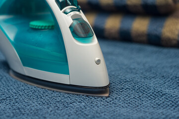  electric iron lies on a table near clean blue towels.