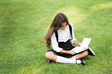 small girl reading book. literature for kids. write childhood memories. her diary. making notes in notebook. back to school. kid study in park. relax on green grass with interesting book