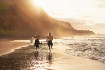 Happy surfers running on beach with surfboards - Sporty friends surfing and training on vacation in...