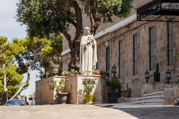 The large stone statue of the Virgin Mary in the courtyard of the Stella Maris Monastery which is located on Mount Carmel in Haifa city in northern Israel - obrazy, fototapety, plakaty