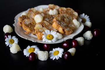 Homemade dessert for children from toffee, butter and corn sticks on a white antique plate with a gold rim, decorated with corn sticks and daisies.