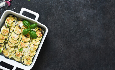 Zucchini casserole with cream, garlic and parmesan on a black background. View from above.