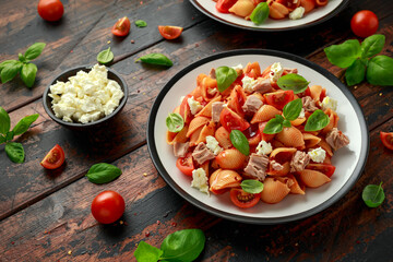 Conchiglie Tuna pasta with tomato sauce, feta cheese and basil on wooden table. healthy food