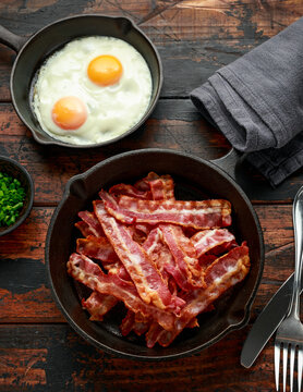 Fried crunchy Streaky Bacon pieces in a cast iron skillet