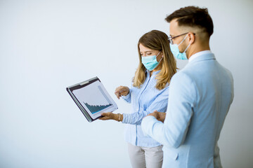 Business partners standing and looking at business results in office  while wearing face masks sa an virus protection
