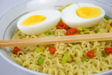 Bowl Of Instant Noodle With leek, Red Chilli and Bamboo Chopsticks On White Background