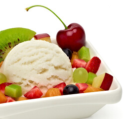 Fruit salad with vanilla ice cream scoop in bowl on white background