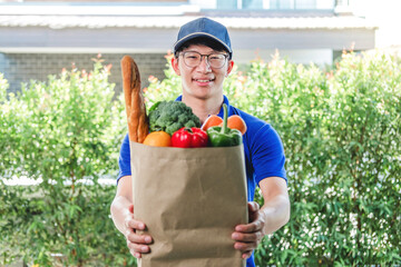 Food Delivery concept. Asian delivery man hand giving bag of food, fruit, vegetable delivery to costomer grocery delivery service.