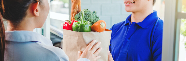 Food Delivery concept. Asian woman hand accepting bag of food, fruit, vegetable delivery from professional deliveryman Postman and express grocery delivery.