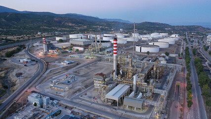 Aerial drone photo of industrial oil and gas plant in Corinth area overlooking Saronic gulf at dusk, Attica, Greece