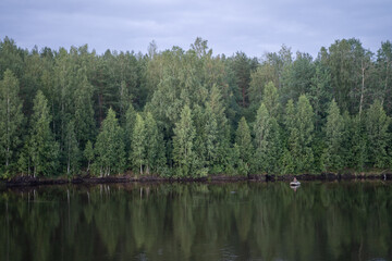 Trees are reflected in the water. Boat view