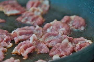 Frühstücksspeck, Schinkenspeck, Bacon beim Anbraten in einer Pfanne, American breackfast