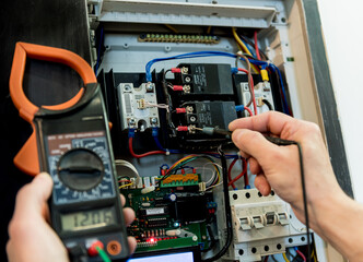 The man is repairing the switchboard voltage with automatic switches.