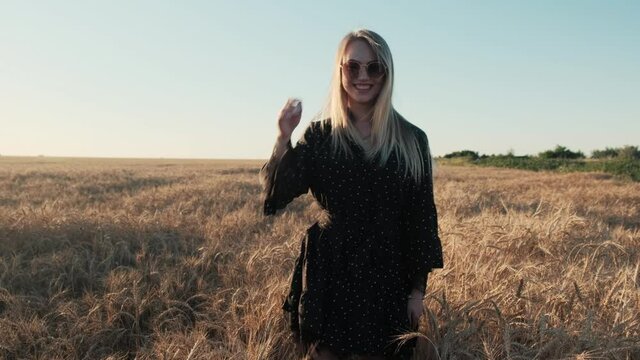 Happy blonde girl runs on a wheat field. Beautiful sunset sun summer evening.
