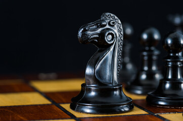 Chess with a black knight in an open area. Black background.