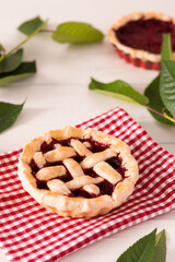 Open pie from shortcrust pastry with cherries and raspberries, a pie with a serviette on a white background