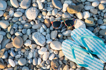 Blue Bright Flip-Flops and Sunglasses on a Stone Beach Background