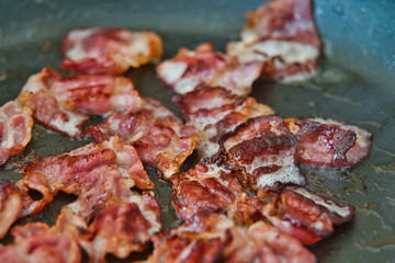 Frühstücksspeck, Schinkenspeck, Bacon beim Anbraten in einer Pfanne, American breackfast