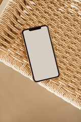 Blank touch screen mobile phone on wicker background. Flat lay, top view empty copy space mockup template. Minimal internet, social media concept