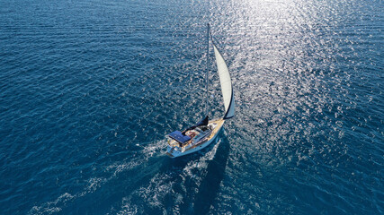 Obraz premium Aerial drone photo of sail boat cruising in the deep blue Aegean sea, Cyclades, Greece