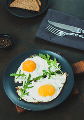 Fried egg. Fried egg with herbs on black plate on black background