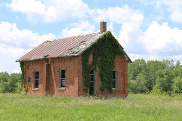 Fototapeta na wymiar abandoned overgrown brick old school house building