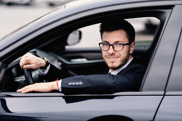 Cheerful business man driving alone in his new car
