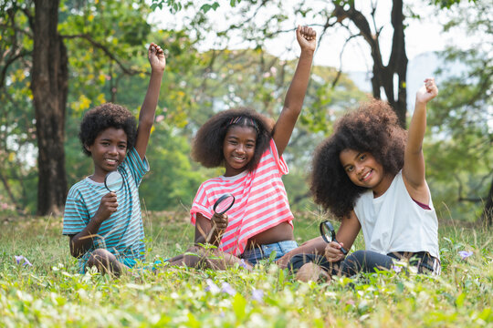 African American children sitting in the grass and looking through the magnifying glass between learn beyond the classroom