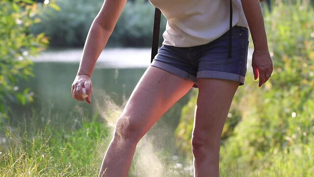 Woman applying insect repellent against mosquito and tick on her legs during hike in nature. Skin protection against insect bite