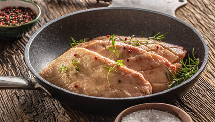 Seared duck breasts with seasonings in a pan on a rustic wood