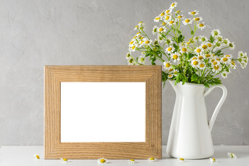 White chamomile flowers bouquet with blank photo frame on white background. mock up. still life