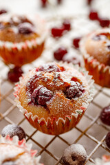 Homemade cherry muffins sprinkled with powdered sugar on a cooling tray close up view