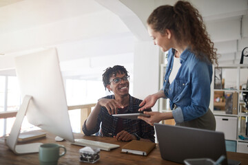 Portrait of female IT developer talking to smiling African-American colleague while standing by...