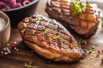 Close up view of freshly roasted duck breasts with pepper seasoning and fresh herbs on top