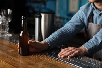 Night lifestyle. Bartender gives bottle of beer without label for client