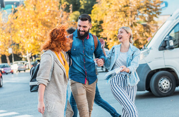 Group of tourists enjoying on vacation, young friends having fun walking on city street during the day.