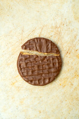 Delicious hocolate covered cookie or biscuit broken in two on plastic chopping block.