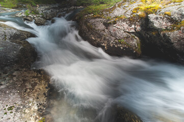 river runs swiftly from the mountains around the stone shore close-up